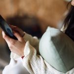 Kobieta na kanapie ogląda nagranie na smartfonie