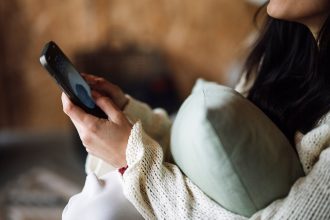 Kobieta na kanapie ogląda nagranie na smartfonie