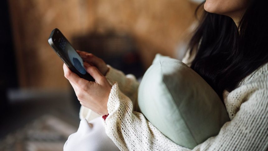 Kobieta na kanapie ogląda nagranie na smartfonie