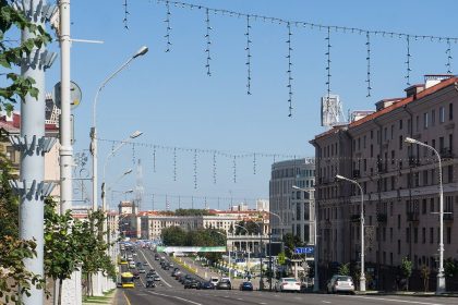Aleja Niepodległości w Mińsku w słoneczny dzień, ruch samochodowy i kamienice