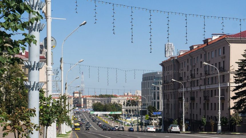 Aleja Niepodległości w Mińsku w słoneczny dzień, ruch samochodowy i kamienice