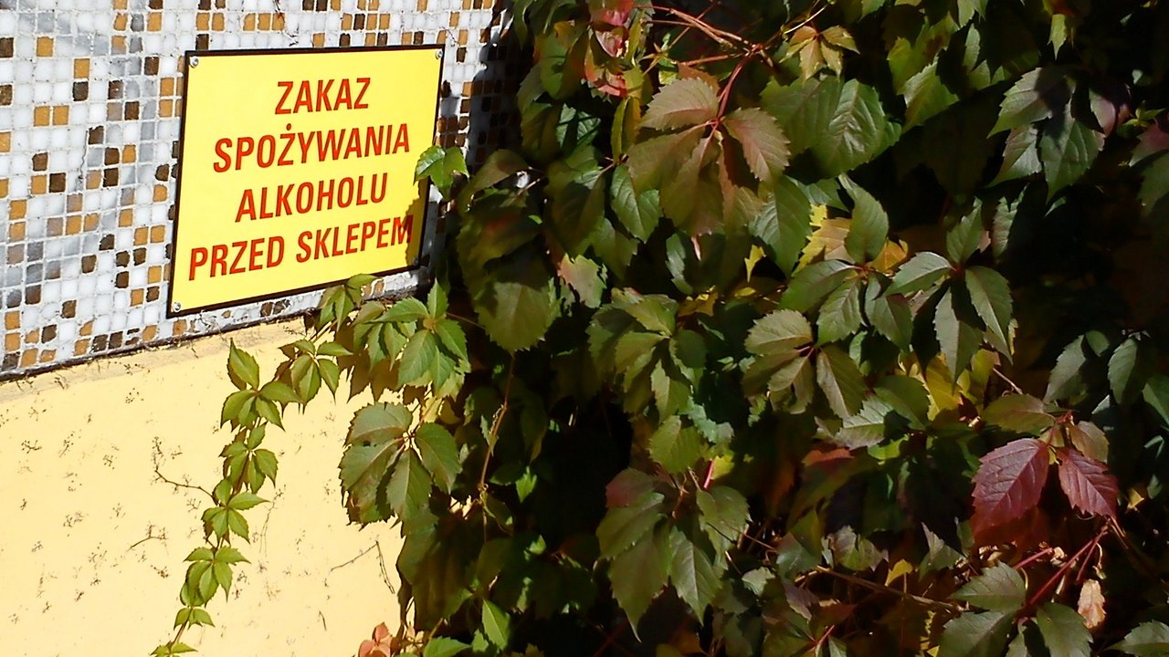 Tabliczka „Zakaz spożywania alkoholu przed sklepem” na ścianie sklepu w Poznaniu